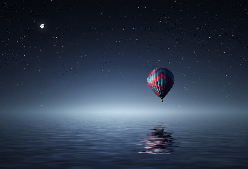 A serene hot air balloon floating over the ocean under a starry night sky.